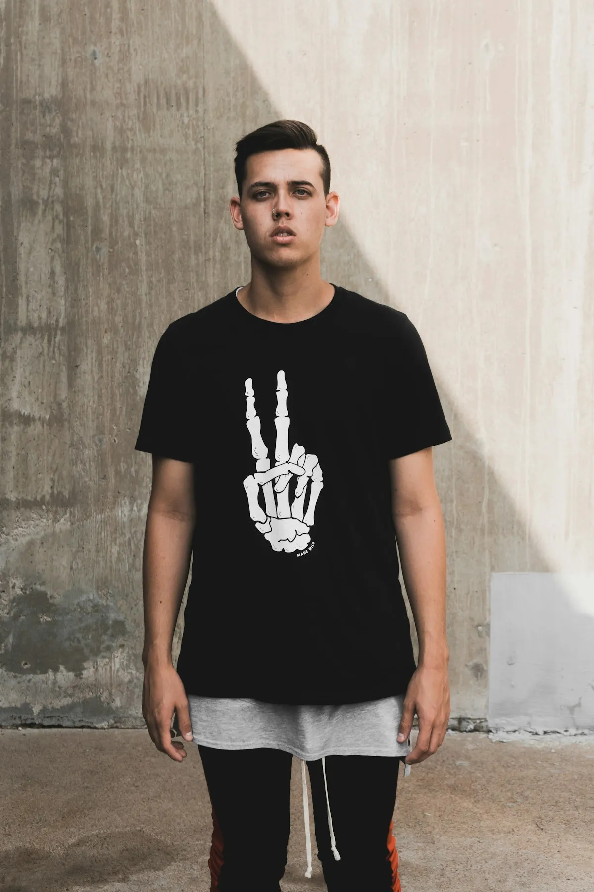 スケルトンハンドのグラフィックが入った黒Tシャツを着た若い男性