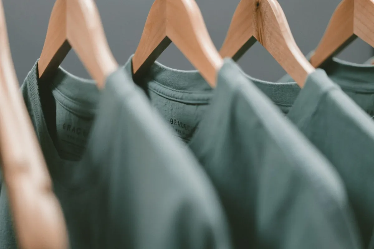 セージグリーンのTシャツがハンガーに並んでいる